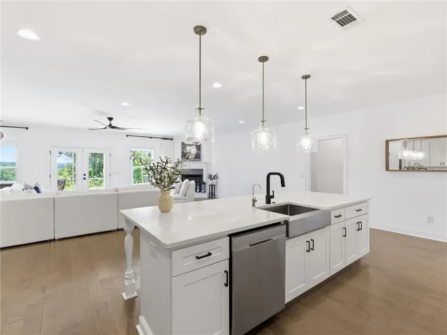 An open-concept living space integrates a pristine kitchen island with a cozy living area, offering clear outdoor views.
