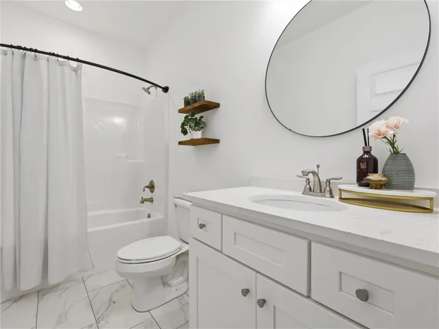 Marble-look flooring and a clean vanity define this bright and inviting full bathroom.