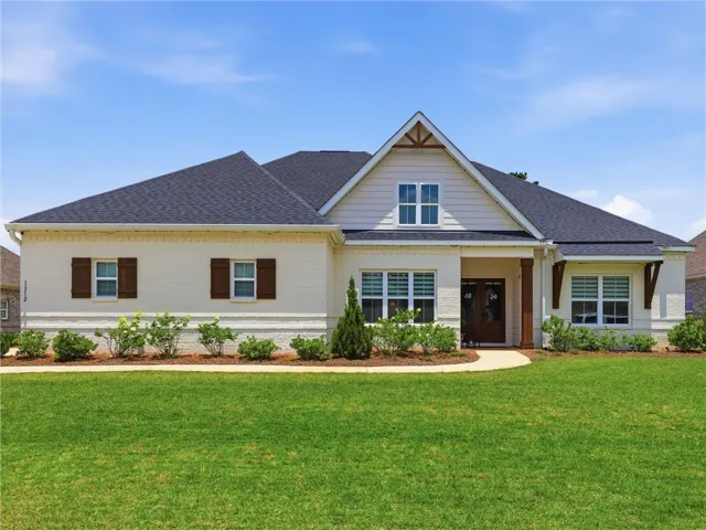 Well-maintained grounds frame this appealing home with a dark shingle roof and contrasting white brick.