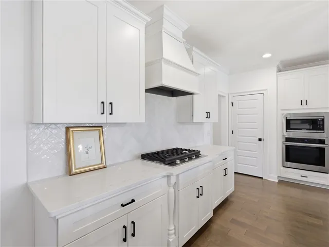 White cabinetry, solid surface counters, and modern appliances outfit this sleek kitchen.