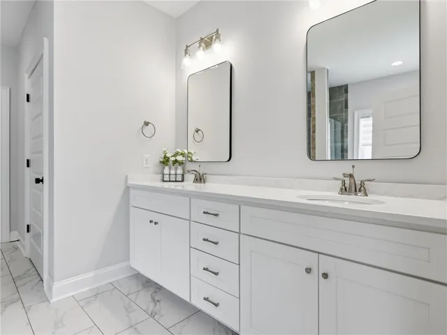 Dual vanities and sleek mirrors adorn this pristine primary bathroom, offering ample space and contemporary design.