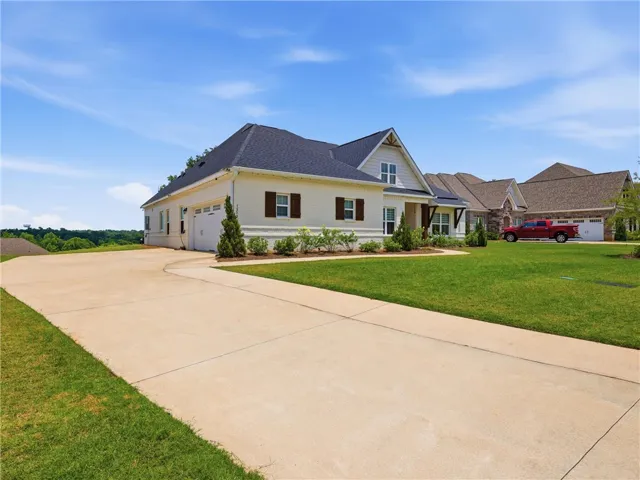 A graceful residence with a wide driveway, manicured lawn, and tasteful exterior detailing awaits.