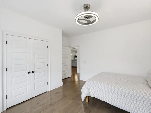 Hardwood floors and a bright overhead light fixture define this welcoming bedroom.