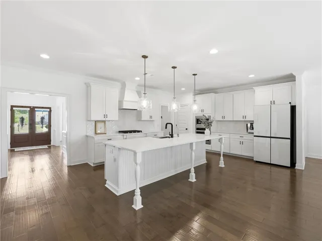 A well-lit kitchen with a spacious island, white cabinetry, and gleaming hardwood floors awaits.