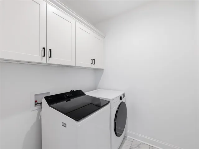 Ample cabinetry and modern appliances define this pristine laundry space.