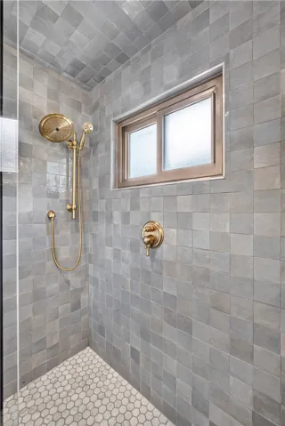 A windowed shower features classic hexagon tile flooring and timeless brass fixtures.