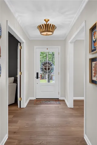 A well-lit entry hall with polished  flooring, leading to an inviting glass-paneled front door.