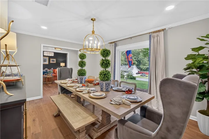 An inviting dining room features wood floors and a statement chandelier, setting a perfect scene for entertaining.