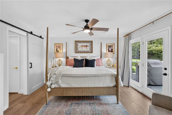 A naturally illuminated sleeping quarter featuring a decorative ceiling fan, with convenient patio access.