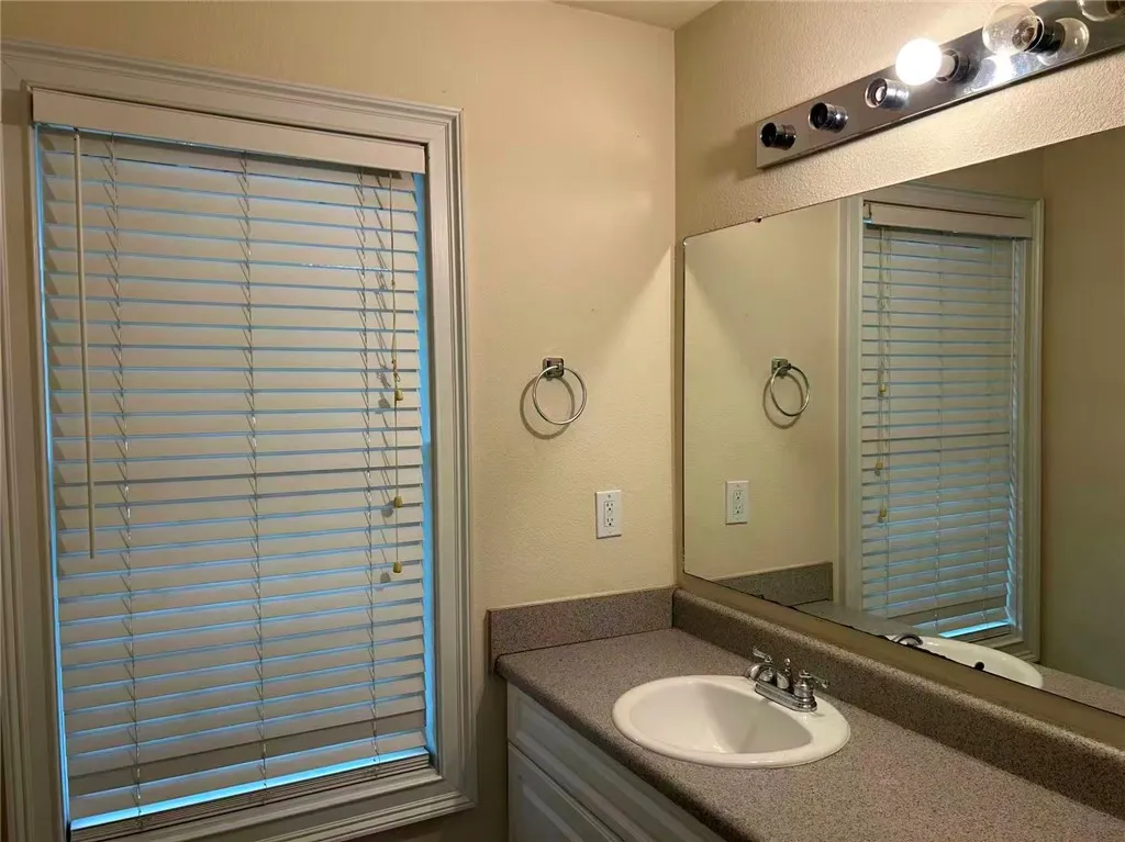 Functional vanity with integrated sink and mirror brightens this bathing space.