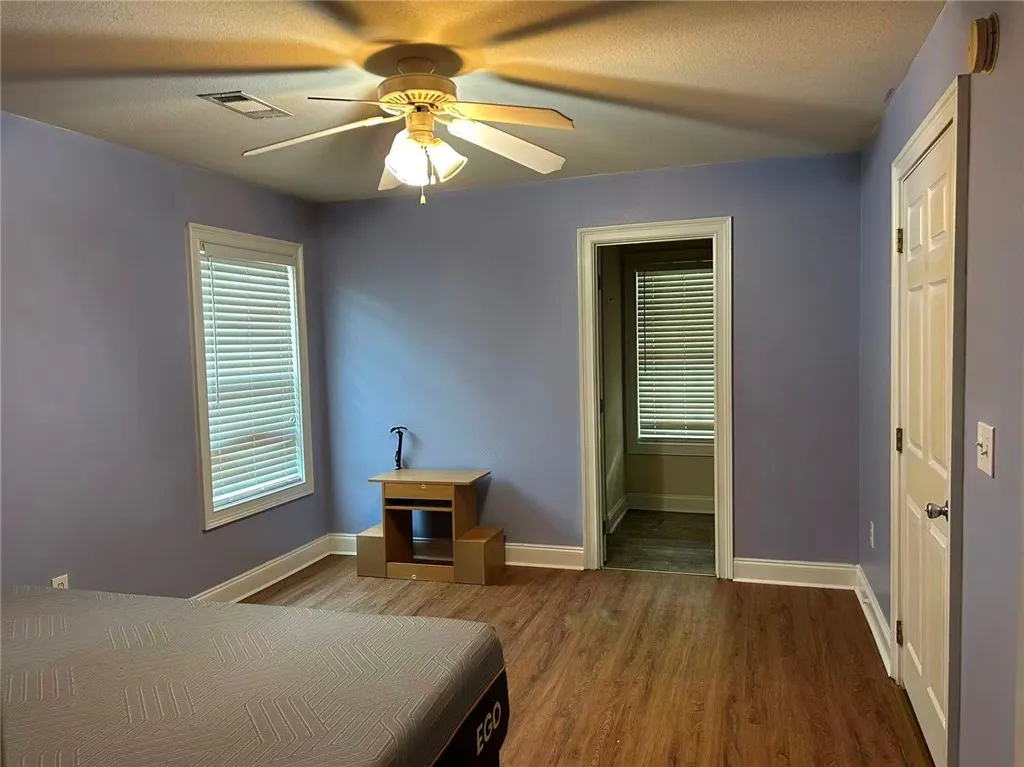 An inviting bedroom features rich hardwood flooring and a functional ceiling fan for comfort.