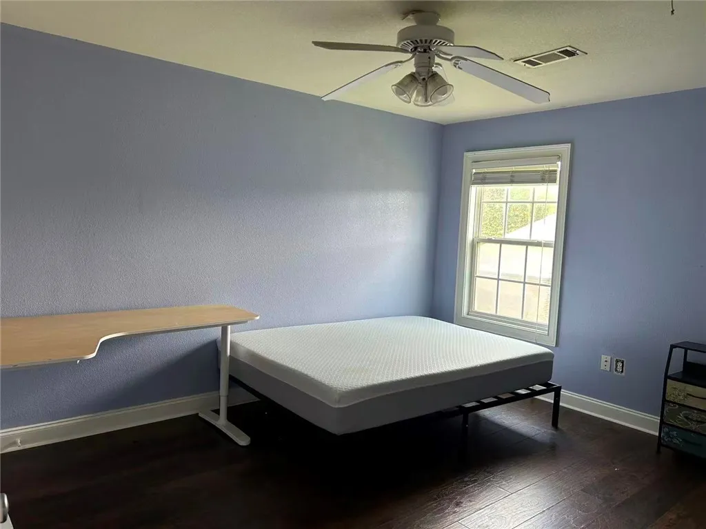 Well-lit room featuring rich hardwood flooring and a functional window.