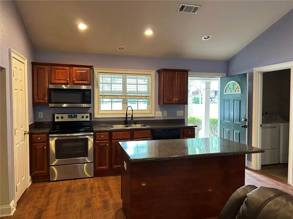 A well-appointed kitchen features rich wood cabinetry, stainless steel appliances, and a central island with countertop.