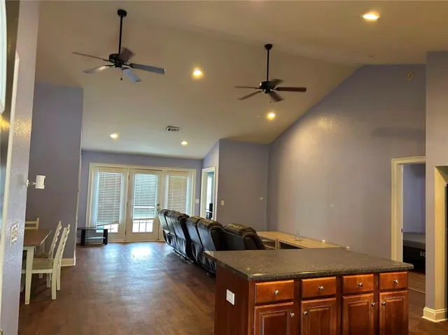 Vaulted ceilings and rich wood flooring define this open-concept living space, leading to outdoor access.