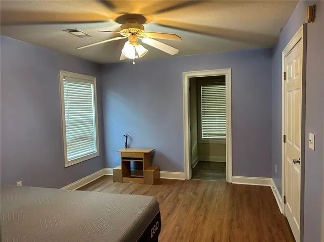 An inviting bedroom features rich hardwood flooring and a functional ceiling fan for comfort.
