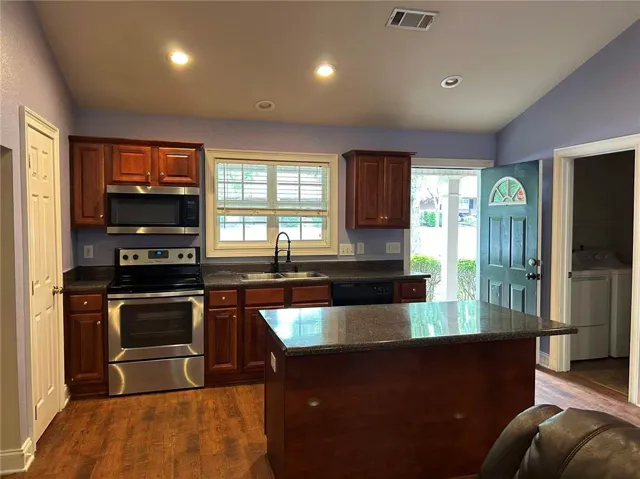 A well-appointed kitchen features rich wood cabinetry, stainless steel appliances, and a central island with countertop.