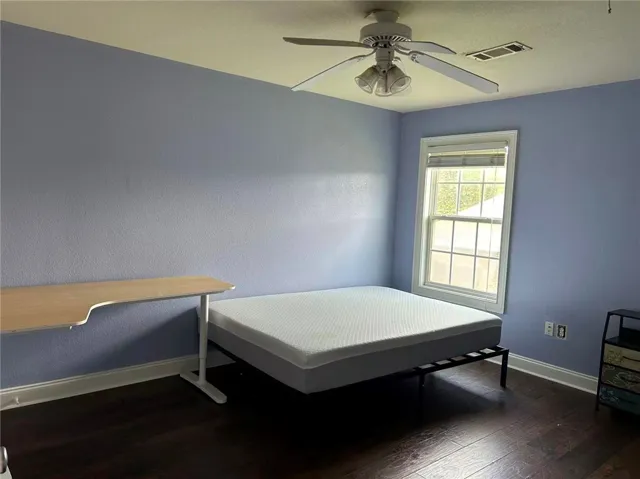 Well-lit room featuring rich hardwood flooring and a functional window.