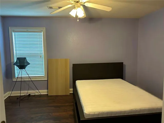 Hardwood flooring and a refreshing ceiling fan elevate this restful space.