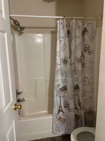 Functional full bathroom offering a tub and shower combination with a decorative shower curtain.