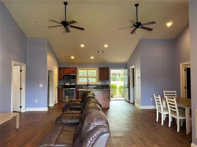 An open concept living area boasts vaulted ceilings, recessed lighting, and rich wood flooring.