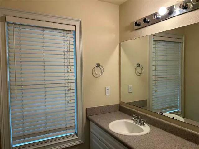 Functional vanity with integrated sink and mirror brightens this bathing space.