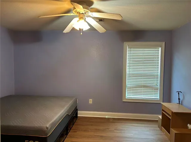 A comfortable bedroom with rich wood flooring and a refreshing ceiling fan for year-round comfort.