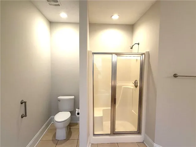 A well-appointed bathroom features a glass-enclosed shower alongside a private commode area.