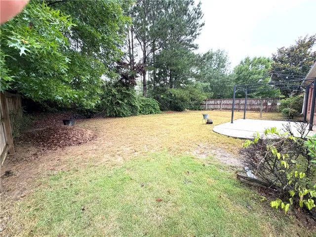 A fenced backyard offers a concrete patio with a pergola frame, ready for outdoor enjoyment.