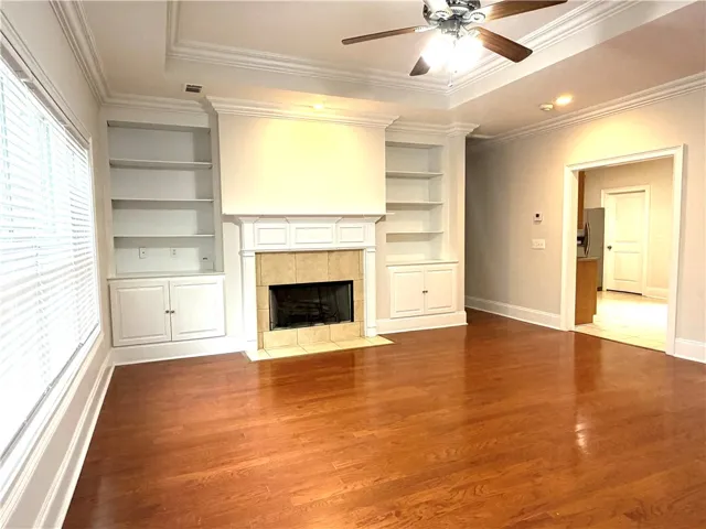 Hardwood flooring extends throughout this well-appointed living space featuring built-in shelving and a cozy fireplace.