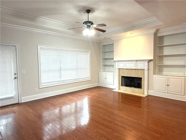 Rich hardwood floors complement built-in shelving surrounding a cozy fireplace, creating an inviting living area.