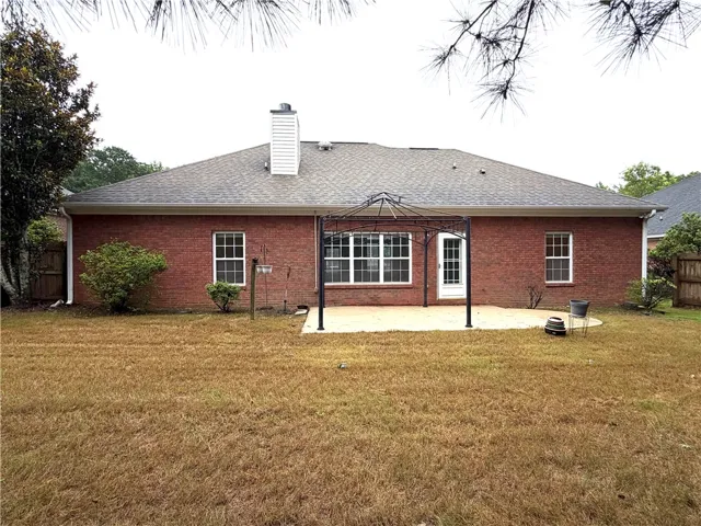 A classic brick exterior meets a tranquil backyard oasis, complete with a paved patio.