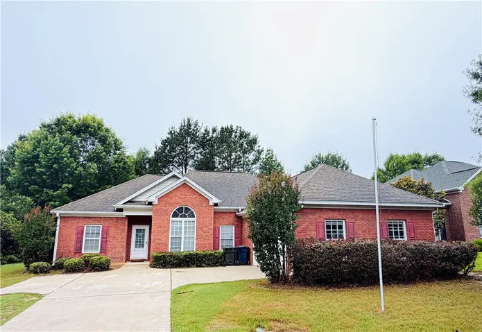 Brick facade with red shutters frames this welcoming single-story residence.