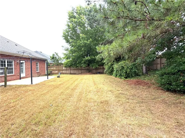 A spacious backyard with mature trees provides ample room for outdoor activities and relaxation.