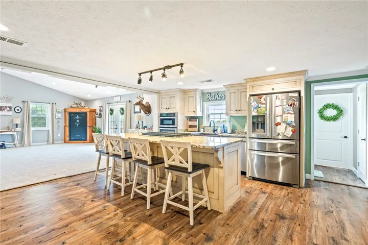 A grand kitchen island with granite counters transitions to a light-filled living area with vaulted ceilings.