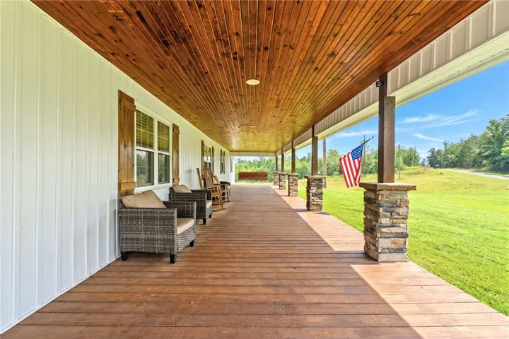 A deep, welcoming porch extends along the home, perfect for enjoying tranquil rural views.
