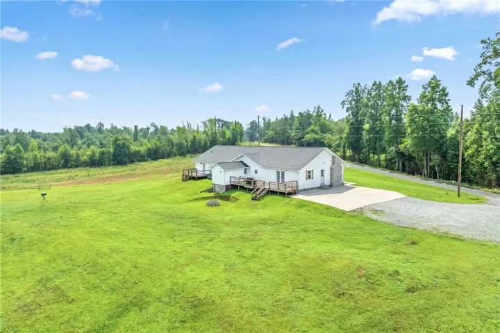 Spacious home with expansive lawns and a picturesque wooded backdrop, perfect for tranquil living.