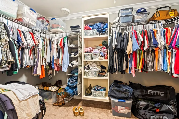 Thoughtfully designed for ample storage, this walk-in closet includes carpeted floors and built-in shelving.