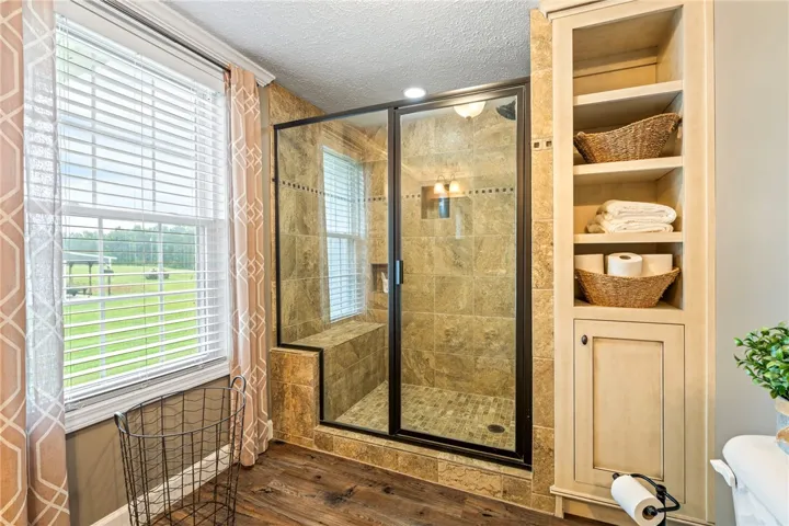 A window-lit bathroom offers a tiled walk-in shower and built-in storage.