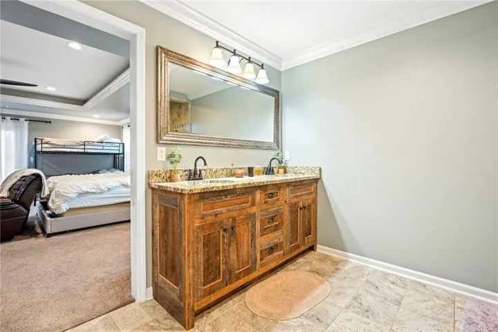 Granite counters and dual sinks define this functional, well-lit bathroom, adjacent to a cozy sleeping area.