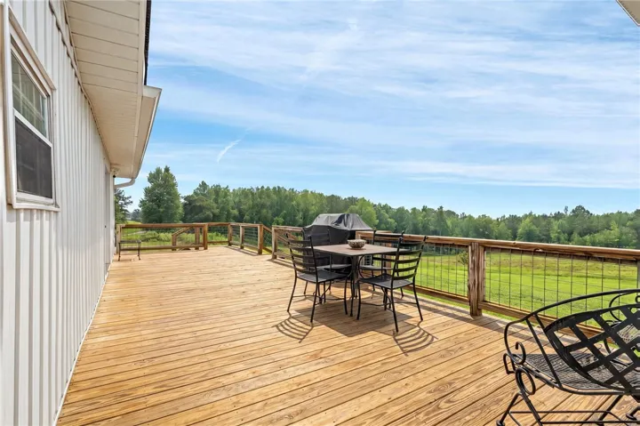 A spacious wooden deck provides generous outdoor living, overlooking a verdant landscape.