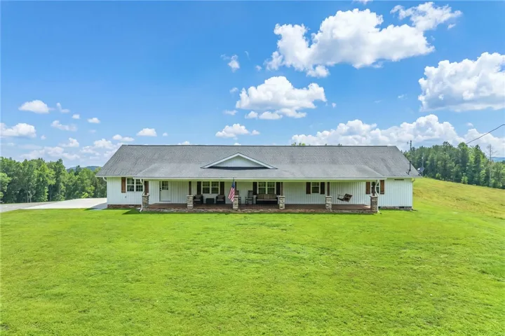 A classic ranch home nestled on a verdant hill, presenting a welcoming long front porch.