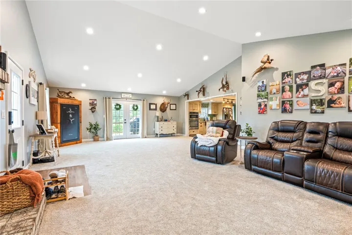 A spacious living area with vaulted ceilings and recessed lighting flows seamlessly to the adjacent kitchen.