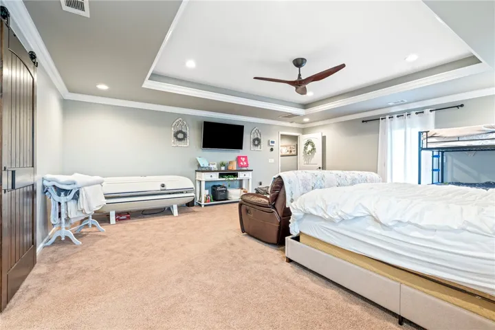 A spacious bedroom features a ceiling fan, recessed lighting, and soft carpeting.
