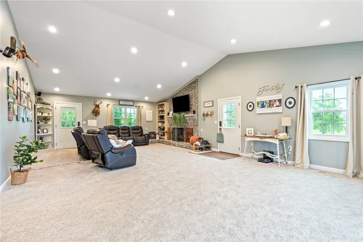 A spacious great room features vaulted ceilings, ample natural light, and a prominent brick fireplace.