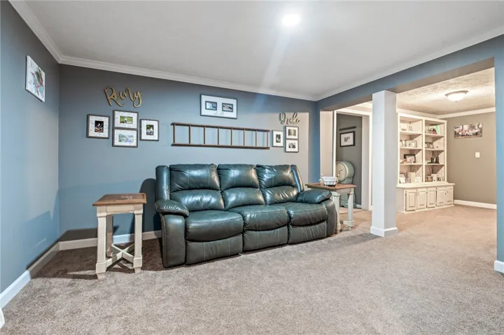 A versatile living area with crown molding, plush carpet, and built-in shelving for optimal organization.