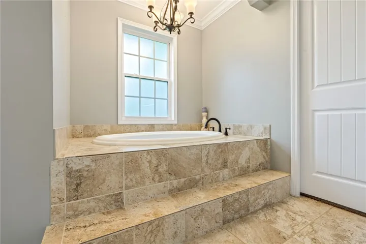 Indulge in a tranquil bathing experience with this inviting built-in tub, set within elegant tiled steps.