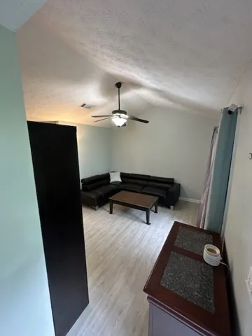 The living area features a high vaulted ceiling and light-toned laminate flooring.