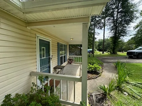 A welcoming front porch with white railings offers a tranquil spot to enjoy the outdoors.