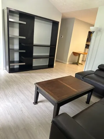 A well-lit living area showcases a sleek, built-in entertainment unit and durable plank flooring.