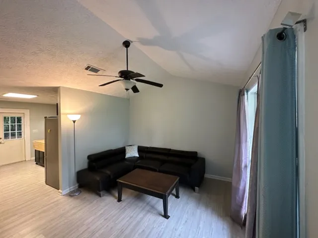 A relaxed living area with a vaulted ceiling and light-toned flooring offers an open, airy feel.